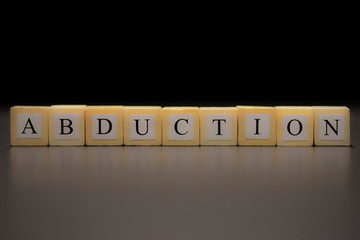 ABDUCTION written on wooden cubes isolated on a black background...