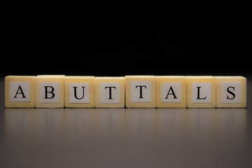 ABUTTALS written on wooden cubes isolated on a black background...
