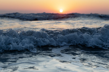 Naklejka na ściany i meble Waves of the Mediterranean Sea with sea foam and spray. Beautiful sea on sunset background. Sundown. Seascape.