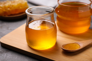 Tasty aromatic honey and wooden board on grey table