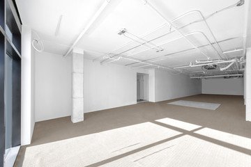 Sunny empty commercial retail space for rent with white walls 
