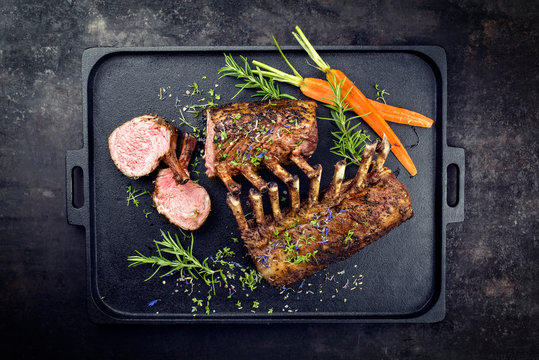 Gegrilltes Lamm Nacken Karree mit Karotten und Kr&auml;uter angeboten als Draufsicht auf einem Modern Design gu&szlig;eisernen Tablett mit Textfreiraum