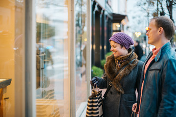 Caucasian couple wearing warm clothing window shopping from outdoors in the winter time.  - 312985084