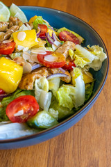 Top view of a homemade chicken salad with mango, tomatoes and fresh onion