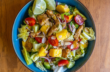 Top view of a homemade chicken salad with mango, tomatoes and fresh onion
