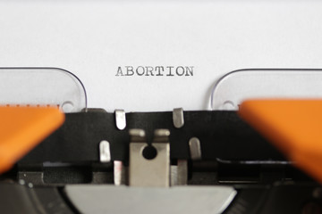 Close up footage of the word ABORTION written on a paper, on an old typewriter with capital...