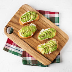 Tasty sandwiches with feta and avocado on the kitchen board. Food concept. Square.