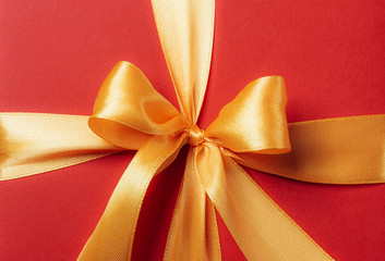 red gift box tied with a golden ribbon. Ribbon tied with a bow on a box. gift concept