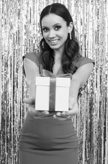 Elegant hispanic brunette woman in luxurious red dress holds a gift box
