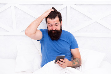 Checking phone first thing in morning. Bearded man use mobile phone in bed. Staying mobile with cell phone. Personal communication. Good morning. Waking up. Phone for keeping in touch