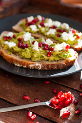 Avocado sandwich on sliced bread toast made with pomegranate and feta cheese