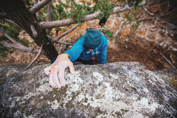 Man climbs boulder.