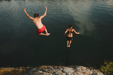 Man and woman jumping into sea