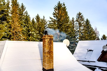 Smoking Winter Chimney . Winter holiday in mountainous areas . to heat the furnace firewood