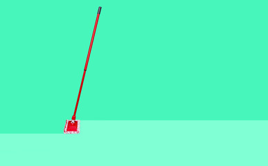 The mop cleans the floor on a pastel mint background. The concept of care for cleanliness, washing of dirt. Cleaning and care for the room.