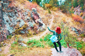 Female hiker taking selfie in mountains forest. A woman saw a beautiful landscape and decided to take a photo.