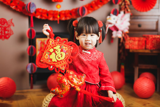 Chinese baby girl traditional dressing up hold a Fu means 'lucky' greeting sign