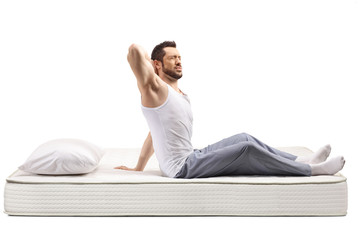 Young man on a bed mattress holding his stiff neck