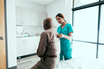 Nurse listening to stethoscope on patient's back