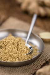 Some Ginger Powder on a vintage wooden table (selective focus; close-up shot)