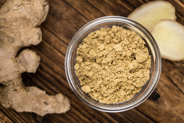 Some Ginger Powder on a vintage wooden table (selective focus; close-up shot)