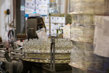 white glass empty beer bottles selective focus, on conveyor belt system machine, craft brewery factory microbrewery bottling warehouse