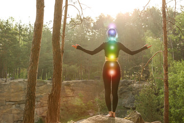 Woman with colorful chakras meditating in forest - obrazy, fototapety, plakaty