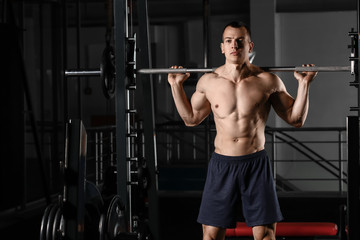 Fototapeta na wymiar Sporty muscular man training with barbell in gym
