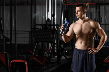 Fototapeta na wymiar Sporty muscular man drinking water in gym