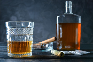 Alcohol, cigar, drugs and money on table. Concept of bad habits