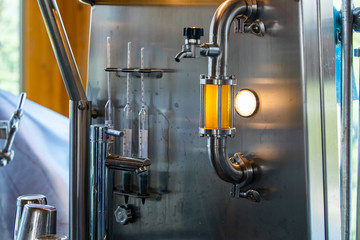 beer quality control equipment, sight glass full of golden beer on stainless steel pipe with light and hose bib faucet valve for taking samples