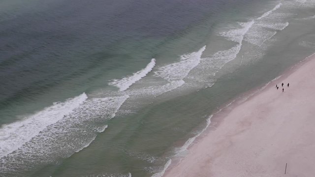 aerial view of tourists exploring the beach and ocean waves rippling in