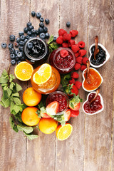 Obraz na płótnie Canvas assortment of jams, seasonal berries jelly, mint and fruits and tangerine