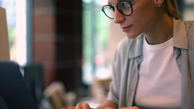 Attractive woman doing ticketing online using protection data website for typing cvv code and making money transfer, girl in classic eyewear choosing web store with delivery service