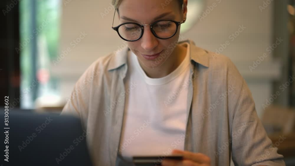 Poster zoom in to female in eyewear doing online transfer with debit card searching good offer purchases in