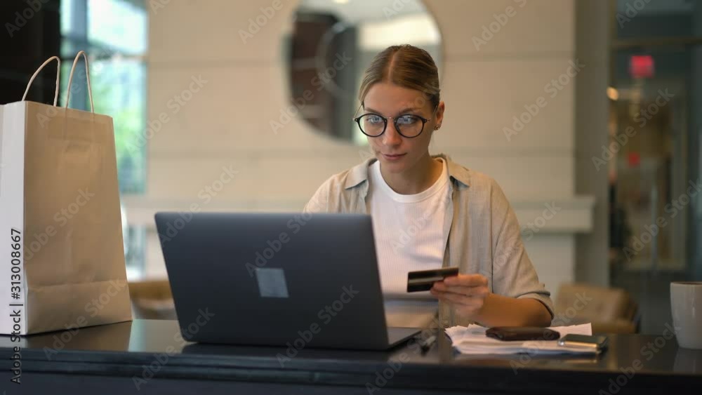 Poster attractive woman in spectacles checking verification cvv code from debit card during ordering delive