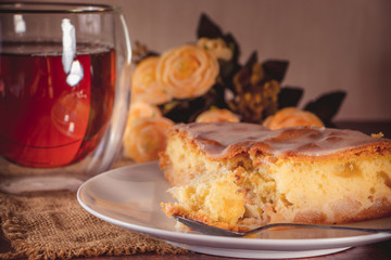 A piece of apple pie on a white plate on a background of yellow flowers