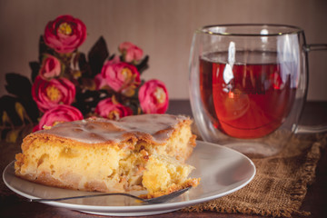 A piece of apple pie on a white plate on a background of pink flowers