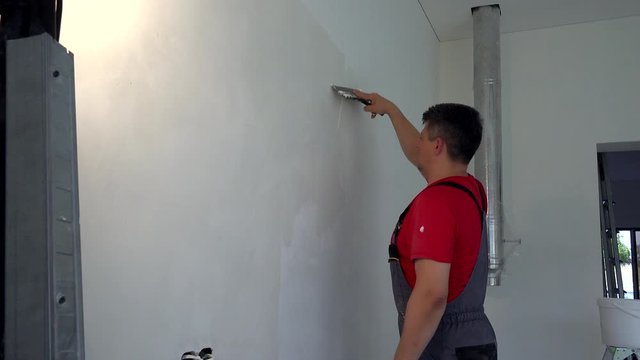 Plasterer man spackling wall with putty. New apartment finishing works