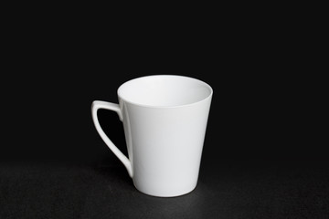 A white porcelain cup is isolated on a black background.