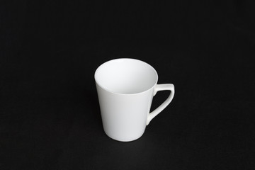 A white porcelain cup is isolated on a black background.