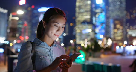 Woman use of cellphone in city at night
