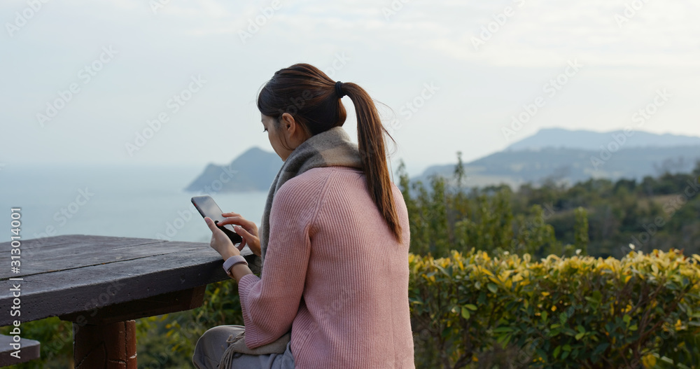 Wall mural Woman use of mobile phone at countryside