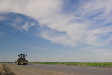 tractor rides on the road in summer against the blue sky in summer. focus on the tractor
