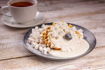 Close-up homemade waffles with creamy ice cream and marshmallows. Cup of tea. Homemade Sweet Dessert