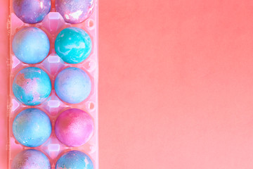 Painted Easter eggs with space intergalactic pattern in stand on coral background