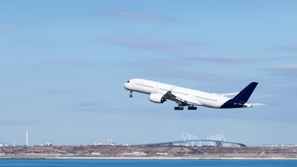 青空の中、ゲートブリッジを背景に離陸する飛行機