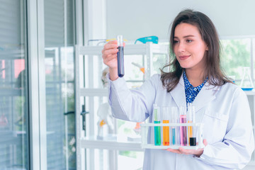 Portrait of happy young attractive smiling woman scientist with tube test in the scientific chemical laboratory Closeup portrait, young smiling scientist in white lab coat standing by microscope. 