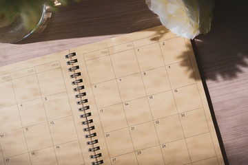 empty message in schedule book of calendar with white rose flower put on table work