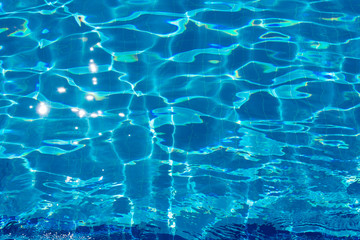 Blue bottom through the transparent water with sunspots of light in the pool